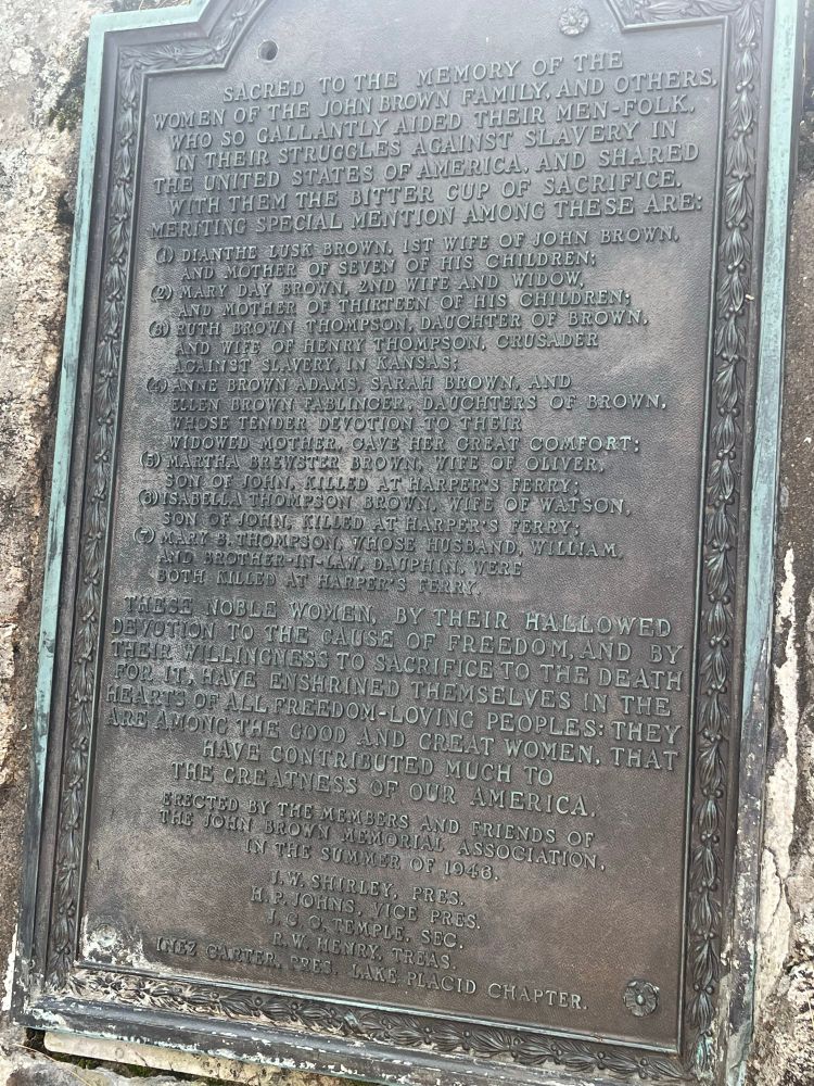 A plaque which reads: “Sacred to the memory of the women of the John Brown family, and others, who so gallantly aided their men-folk in their struggles against slavery in the United States of America. And shared with them the bitter cup of sacrifice. Meriting special mention among these are: 1)Dianthe Lusk Brown, 1st wife of John Brown, and mother of seven of his children 2) Mary Day Brown, 2nd wife and widow and mother of thirteen of his children 3)Ruth Brown Thompson, daughter of Brown. And wife of Henry Thompson, crusader against slavery in Kansas; 4) Anne Brown Adams, Sarah Brown, and Ellen Brown Fablinger, daughters of Brown whose tender devotion to their widowed mother gave her great comfort; 5)Martha Brewster Brown, wife of Oliver, son of John, killed at Harper’s Ferry;
6)Isabella Thompson Brown, wife of Watson, son of John, killed at Harper’s Ferry;
7)Mary B. Thompson, whose husband , William and brother-in-law Dauphin were both killed at Harper’s Ferry. These noble women, by their hallowed devotion to the cause of freedom, and by their willingness to sacrifice to the death for it, have enshrined themselves in the hearts of all freedom-loving peoples:they are among the good and great women that have contributed much to the greatness of our America. Erected by the members and friends of the John Brown Memorial Association in the summer of 1948. J.W. Shirley, Pres. H.P. Johns, Vice Pres. J.C.G. Temple Sec. R.W. Henry Treas. Inez Carter, Pres. Lake Placid Chapter