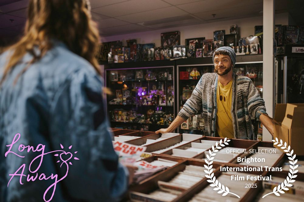 Griffin Kelly as Victoria looking as Justin Lawrence Barnes as Dad, across comic longboxes inside a comic shop, with the Long Away logo
official selection Brighton International Trans Film Festival 2025