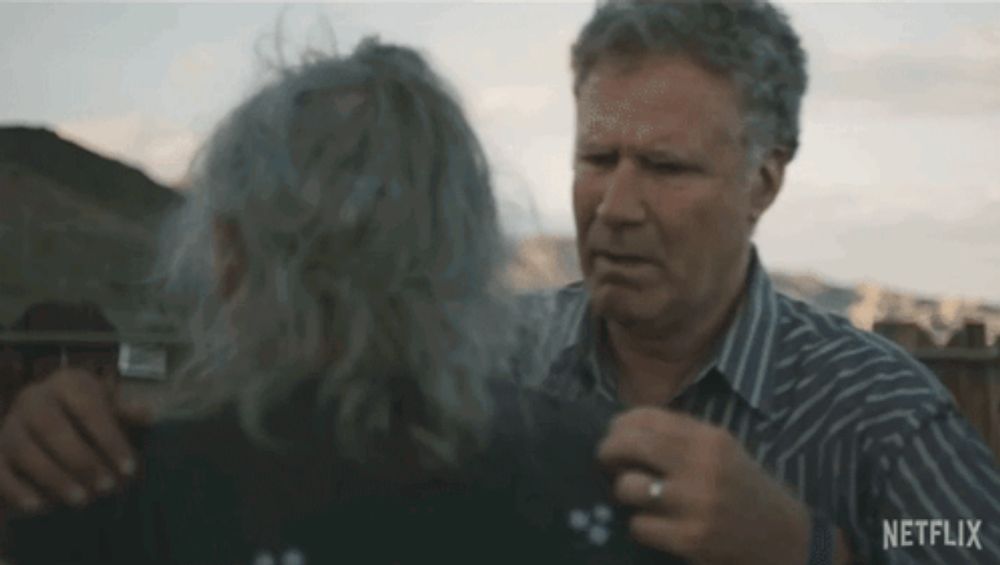 a man in a striped shirt is hugging a woman in a black shirt .