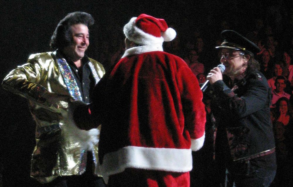 An Elvis Impersonator and someone dressed in a Santa Claus outfit join Bono onstage in Boston on December 5, 2005 during Mysterious Ways on the Vertigo Tour
