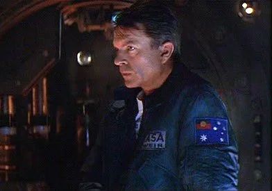 Screenshot from the film Event Horizon showing Dr William Weir, a patch on the sleeve of his jacket shows the Australian flag but the Union Jack has been replaced with the Aboriginal flag