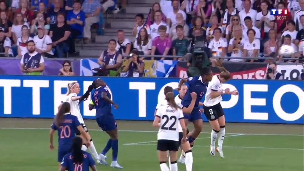 Screenshot from France-Germany soccer match. Different angle of first photo. It shows a German player wearing a white jersey with number 3 grabbing the braids of a French player wearing a blue jersey with number 9. They are inside the box in front of the German goal. You can more clearly see the German player yanking at the French player's hair. Shameful. Don't touch our hair.
