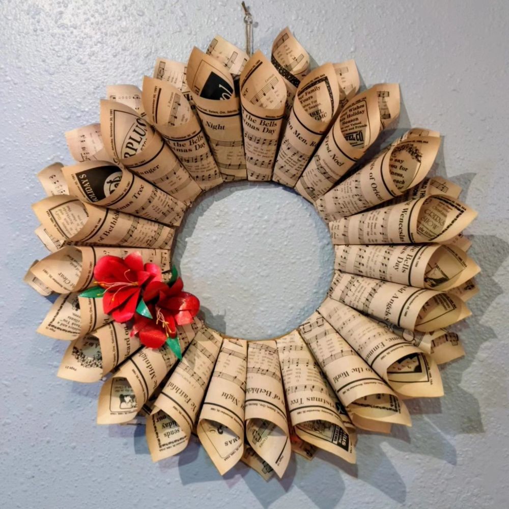 Ten inch cardboard ring with two layers of paper cones glued to it. In the lower-middle left there are two red paper amaryllis flowers with green leaves and yellow stamens.