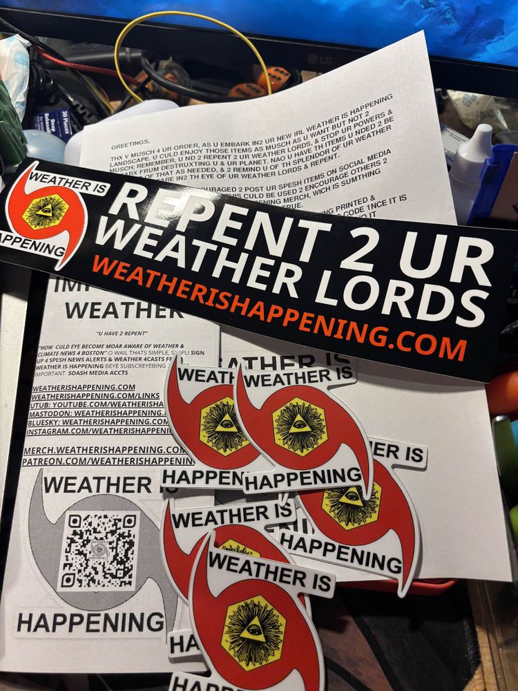 A messy desk with five small WEATHER IS HAPPENING logo stickers, a pamphlet of WEATHER IS HAPPENING propaganda, and a bumper sticker reading REPENT 2 UR WEATHER LORDS, as well as a thank you for ordering note.