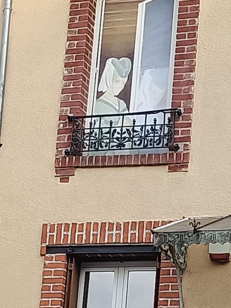 Une étrange dame en vert accrochée sur une fenêtre pour créer un effet malicieux sur les passants