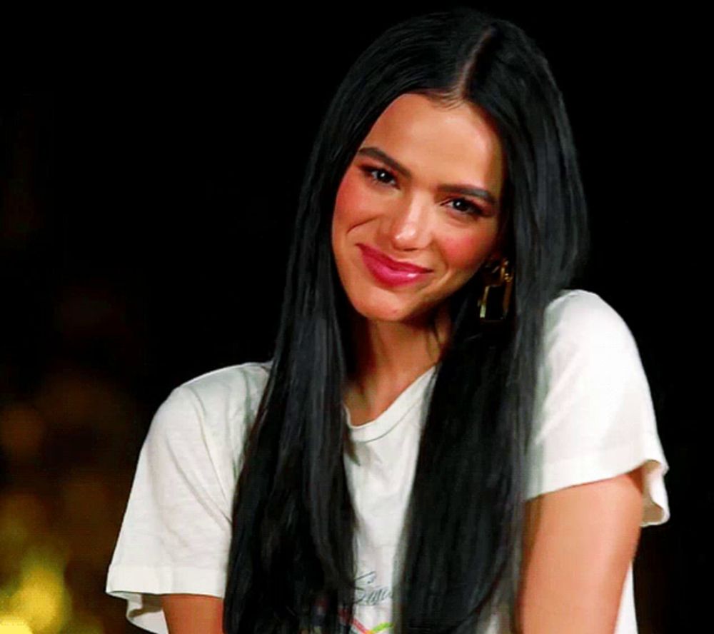 a woman with long black hair is wearing a white t-shirt