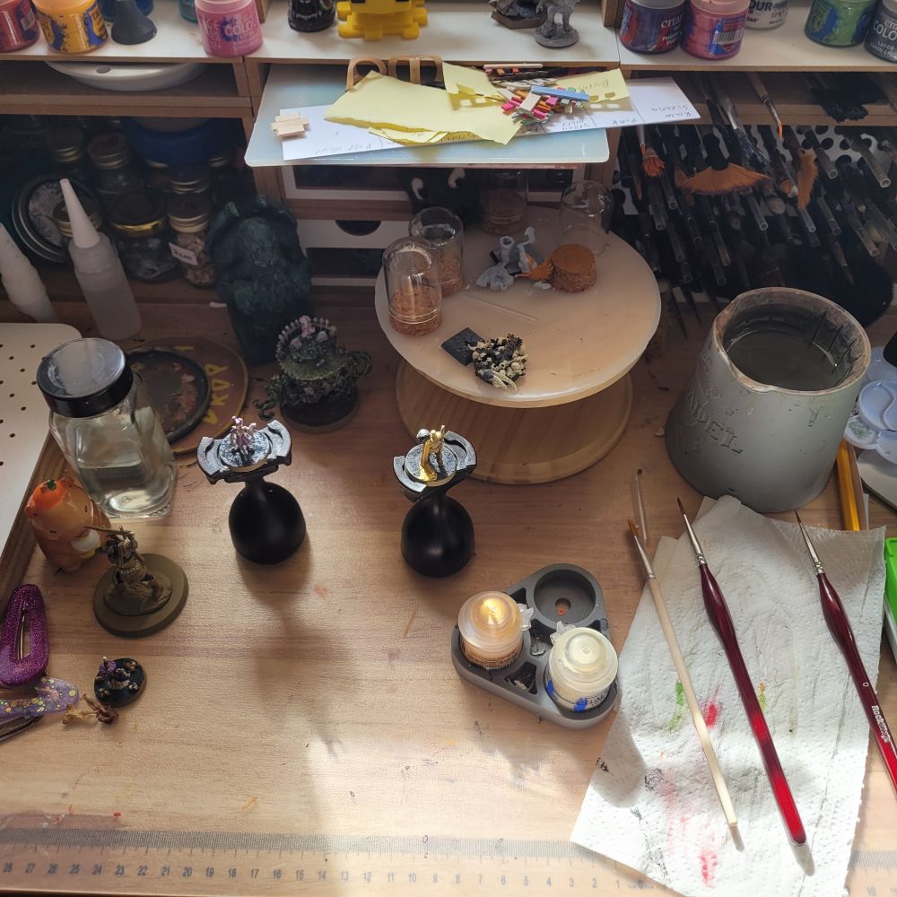 Craft desk with hobbyzone units, in the centre are some painting handles with tiny models on them. 