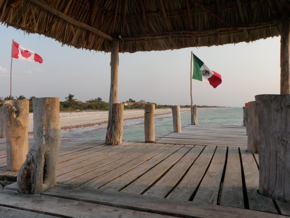 A beach in Mexico, with both a Canadian and Mexican flag visible. 