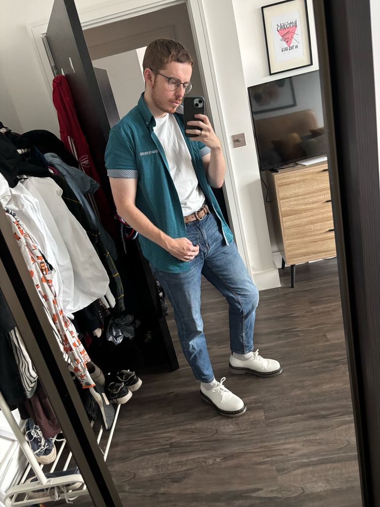 Arthur in a teal over shirt, white t-shirt, jeans and white doc martens