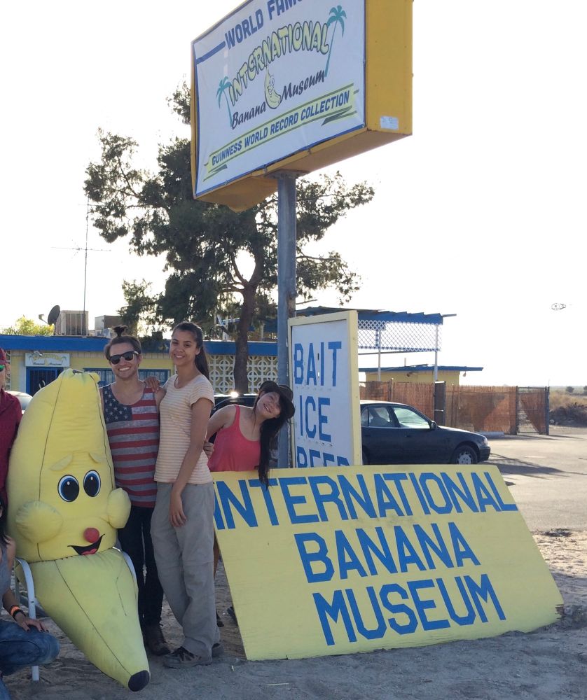 Students posing with sign and banana outside of the international banana museum