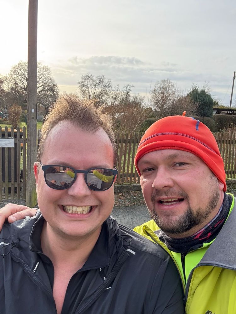 2 Männer nach dem joggen. Einer grinst wie ein Honigkuchenpferd, der andere ist Frank.