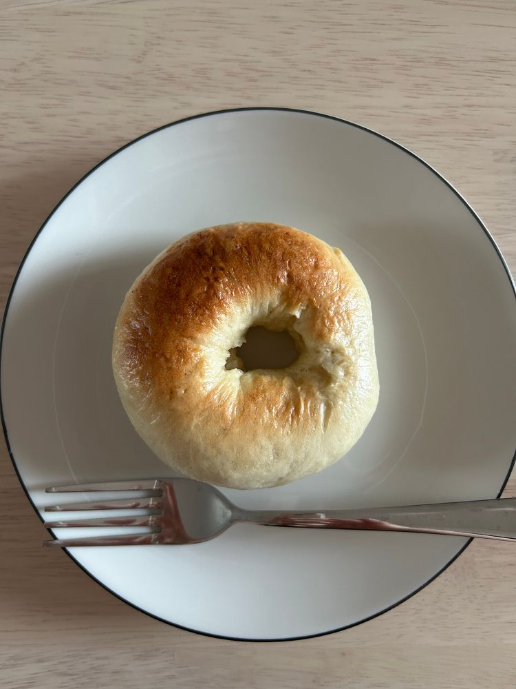 焼けたベーグルをお皿の上に乗せてフォークが添えてある写真です