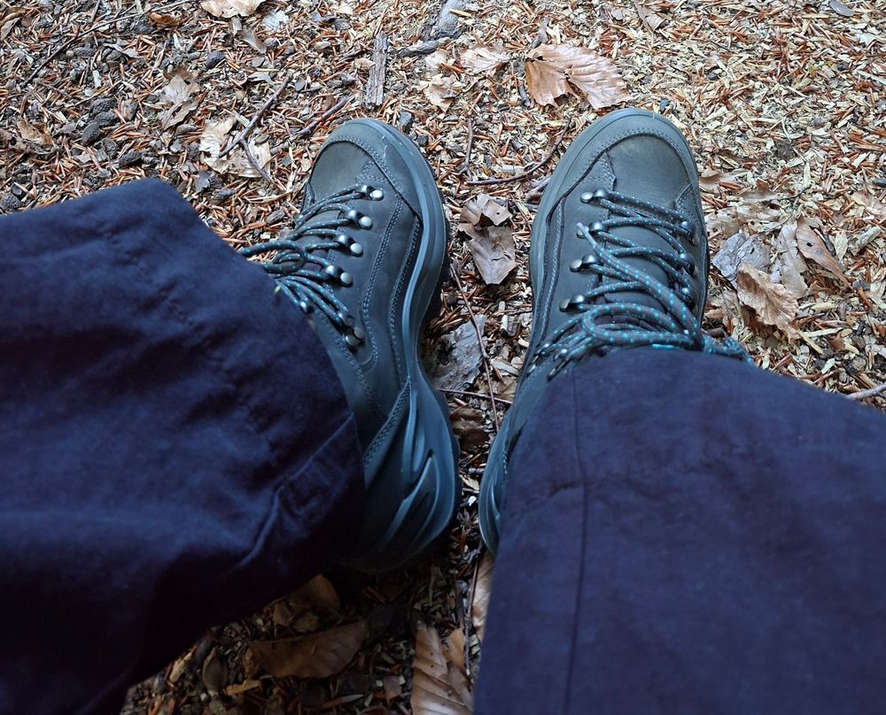 Wanderschuhe mit Leinenhose auf Waldboden