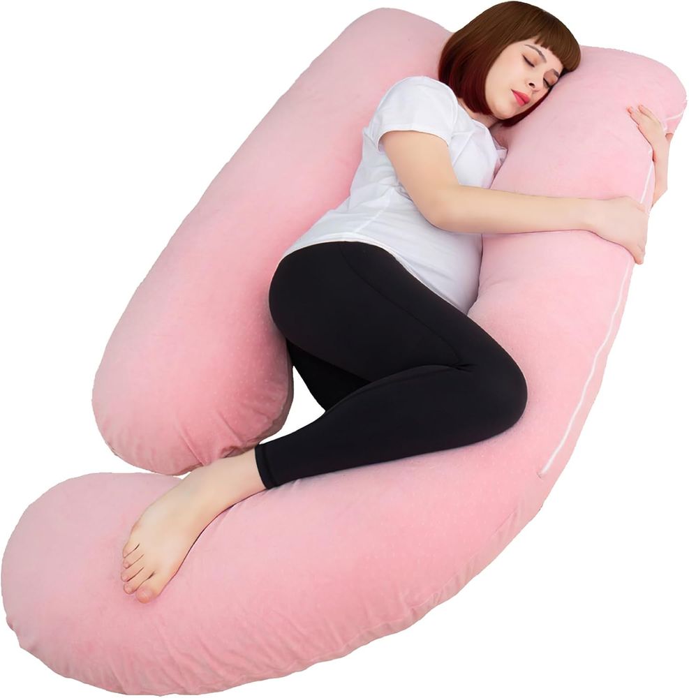 a pink pregnancy pillow with a woman laying in it