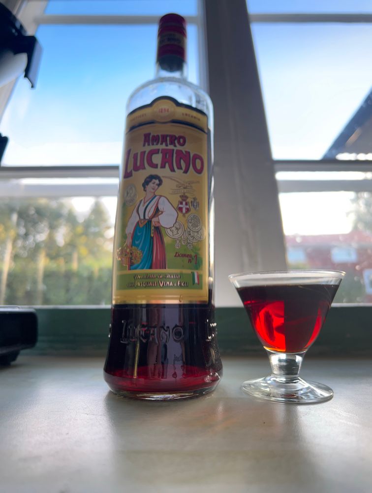 En flaska italiensk örtlikör, och ett litet glas med med rödbrun västs