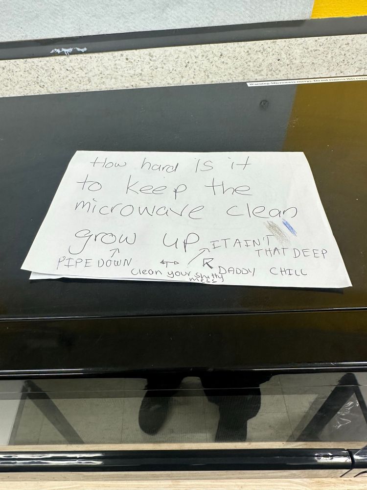 Written note on a microwave saying “how hard is it to keep the microwave clean grow up”
Other writing other people wrote to reply saying  “it ain’t that deep” “pipe down” and “daddy chill”