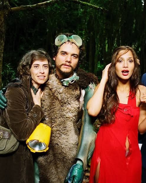 Cena do filme Saneamento Básico, o Filme. Personagem de Fernanda Torres abraça o de Wagner Moura, ao lado de Camila Pitanga de vestido vermelho rasgado.