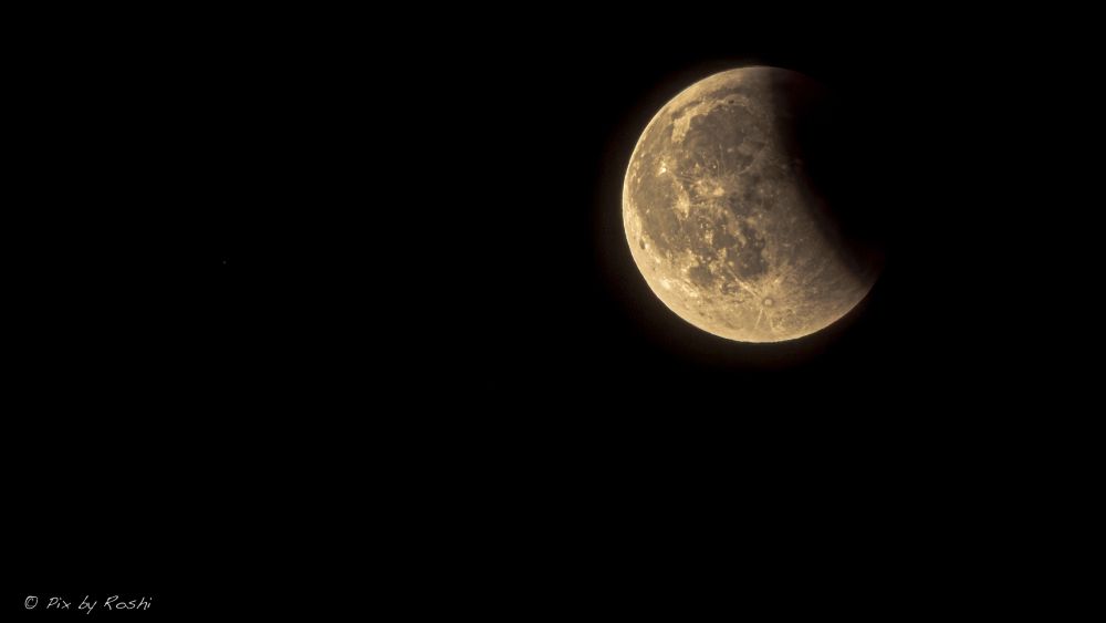 Moon partially eclipsed. Earth's shadow is visible on the right side of the Moon. 
