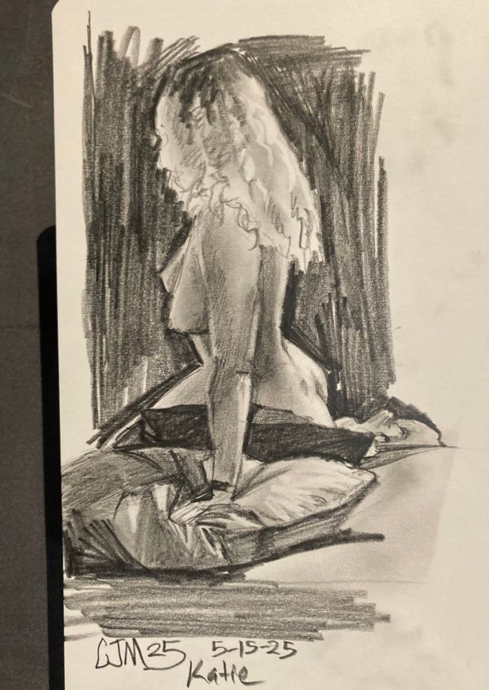 A realistic graphite drawing of a nude woman, seated and propping her body up with her arm. She sits upon two pillows, her face is turned away and covered by her hair. 