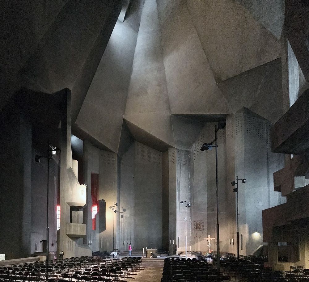 The folded concrete interior of the church, rising high above rows of movable chairs. On the edges one can see the different levels of balconies. Photo by Gunnar Klack via Wikimedia Commons 