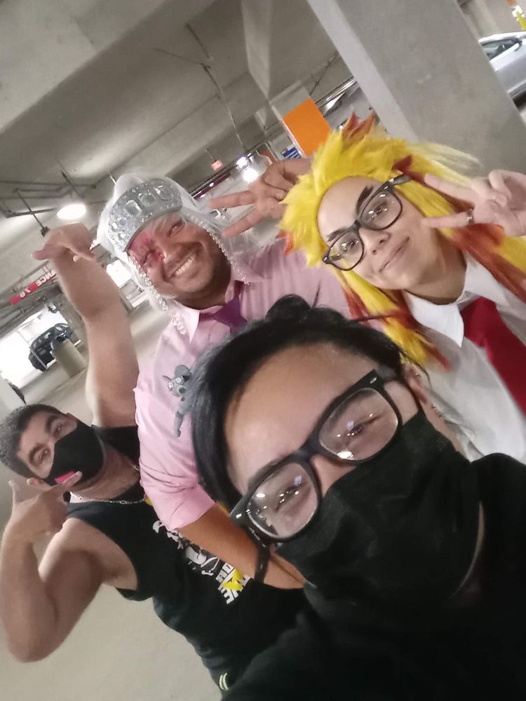 Tengen Uzui and Kyojuro Rengoku cosplayers (in shirt and tie) with friends in a parking garage. 