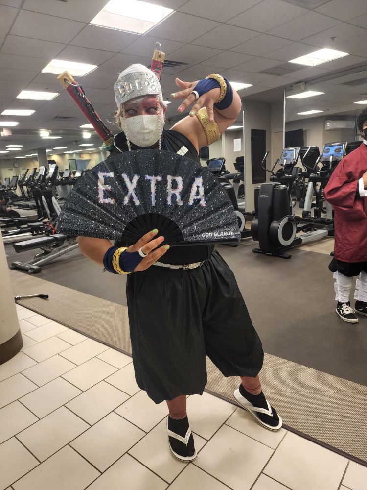 Tengen posing with a sparkly black folding fan that reads "EXTRA" in sparkly white letters.