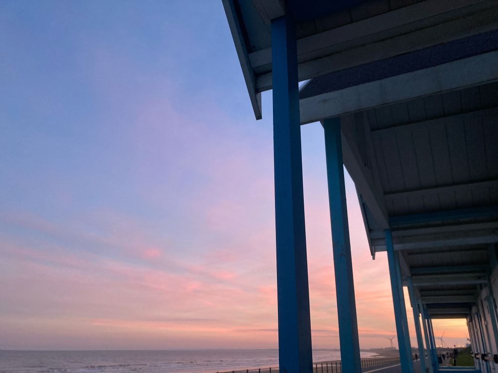 Row of beach huts against the pinky sunset over the sea