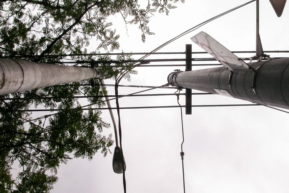 Upward view of two tall utility poles with interconnected power lines against a cloudy sky, conveying an industrial, structured feel.
