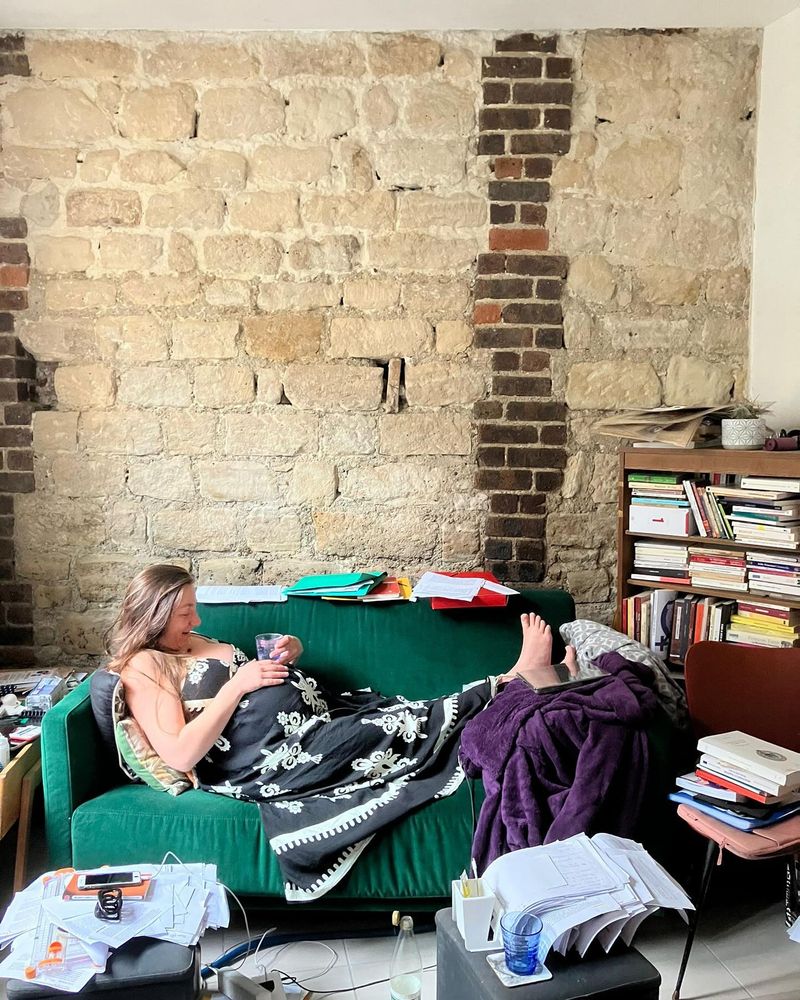 Photographie pre-partum de maman au travail: moi-même sur mon canapé, très enceinte, entourée de liasses de papier (le roman en cours de montage)