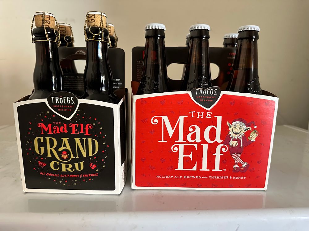 A 4-pack of Mad Eld Grand Cru sits next to 6-pack of 2025 The Mad Elf beer from Troegs brewery.