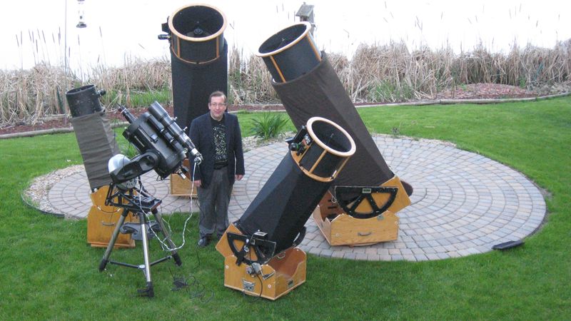 Retired meteorologist Mike Lynch standing next to his collection of giant telescopes.