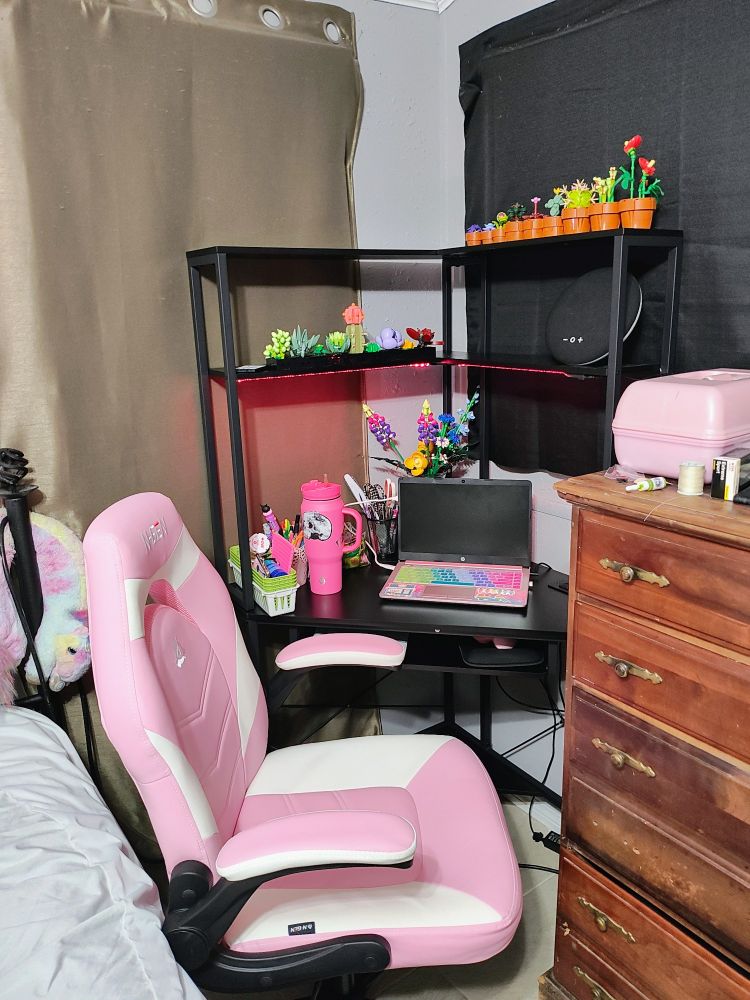 Corner desk with a pink laptop, pink cup and pink desk chair with Lego plants 