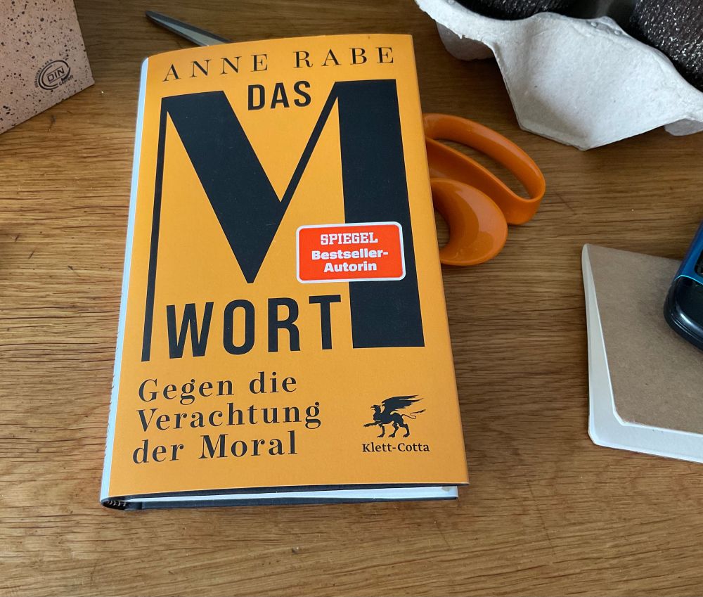 Gebundenes Buch in leichtem Orange mit schwarzer Schrift ‚Anne Rabe, Das M-Wort, Gegen die Verachtung der Moral mit Aufkleber SPIEGEL Bestseller Autorin aus dem Verlag Klett-Cotta