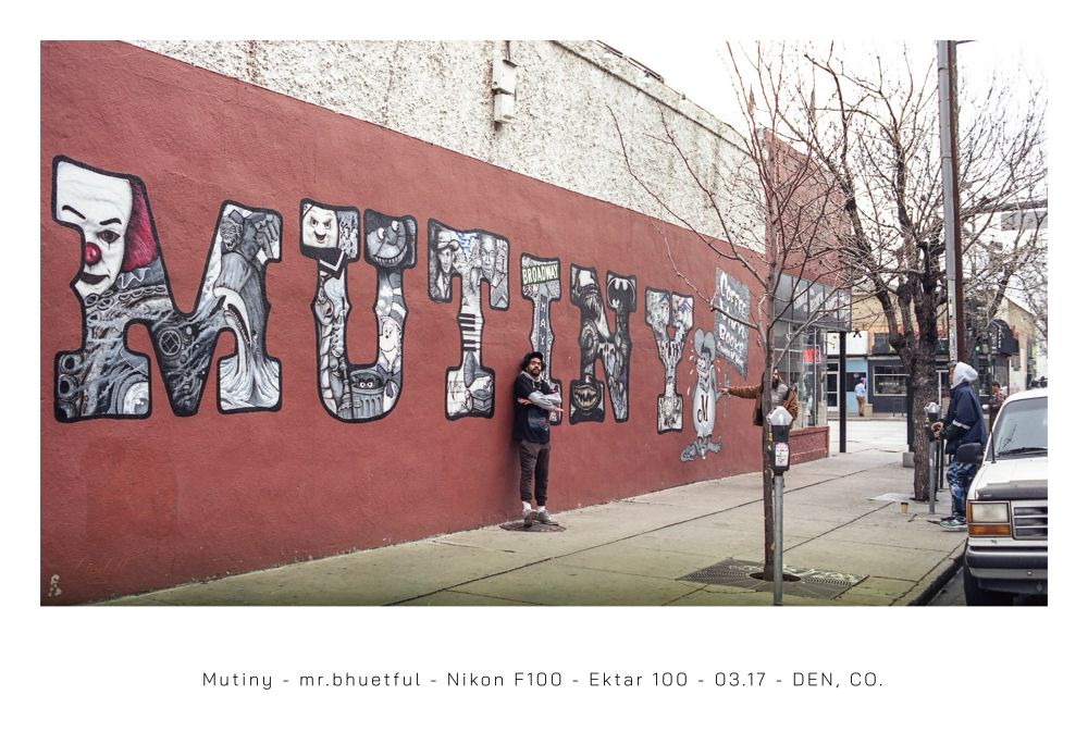 A 35mm film photograph of a young black man standing with his back to a red wall off Broadway in Denver, Colorado that reads “MUTINY” in a western circus font.

Captured on a Nikon F100 w/ has developed 35mm Kodak Ektar.
