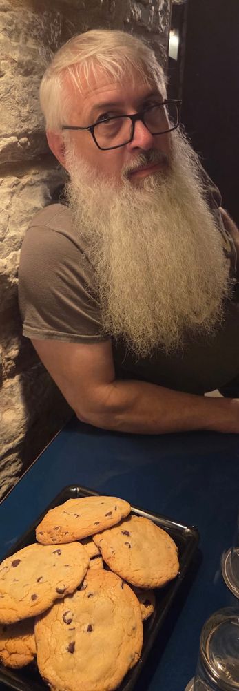 James Pozenel leaning on a table with a plate of chocolate chip cookies. 