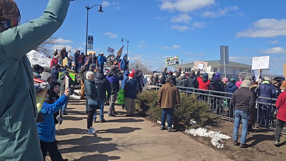 Crowd of people at Hands Off protest. Many holding signs. 