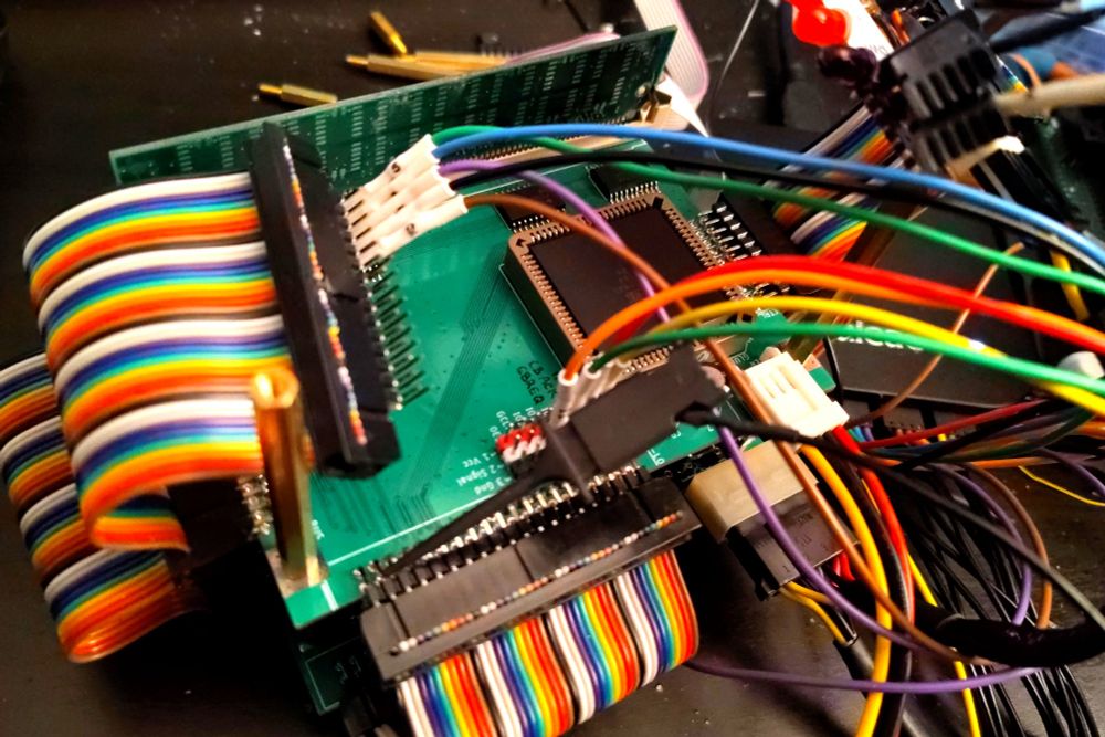 A mess of rainbow-colored wires and logic analyzer probes attached to a sparsely-populated printed circuit board.
