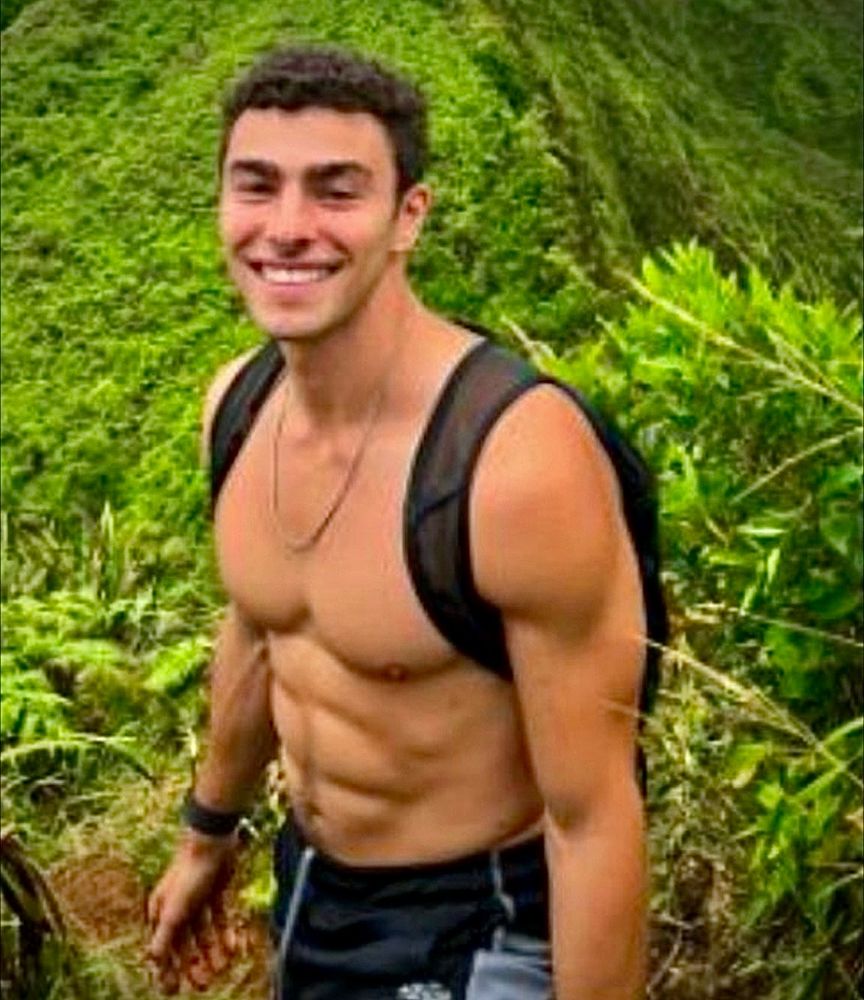 Shirtless muscular Luigi looking sexy and happy hiking through the lush green rainforest hills. 
