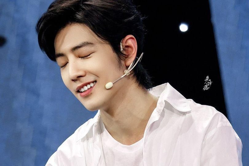 Xiao Zhan, smiling, eyes closed. He is wearing white.
