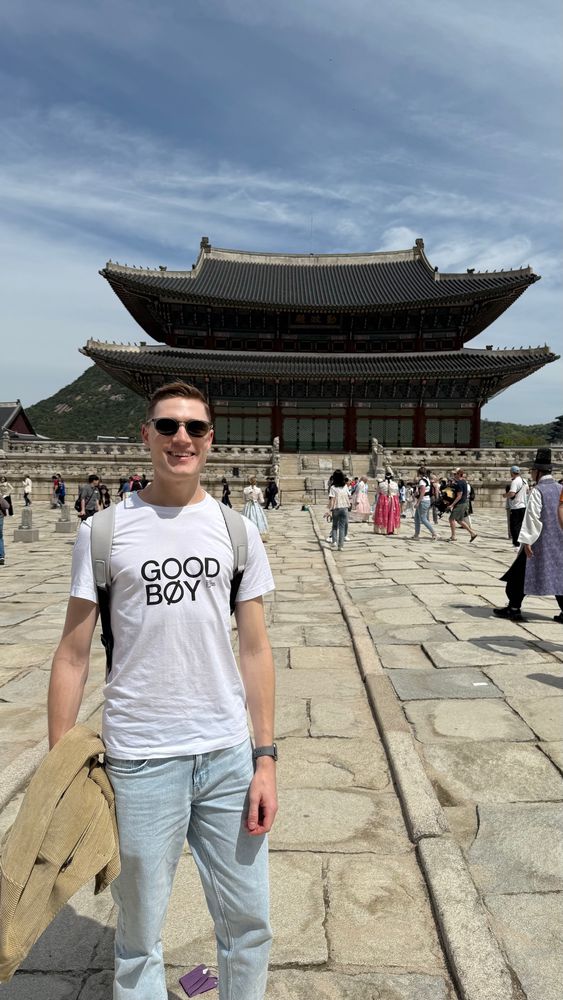a photo of me in standing in front of a palace in Korea. Im wearing sunglasses and a white shirt that says good boy.
