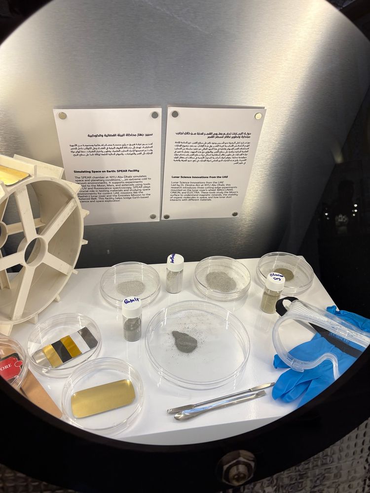 A display case contains: Petri dishes with samples of rock dust, assorted lab tools, and a couple of blocks of text (each in Arabic and English) explaining Moon- and Mars-related experimental work being done in CASS at NYU Abu Dhabi