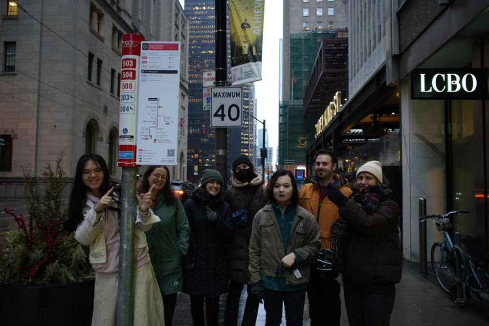group of seven volunteers standing near sign