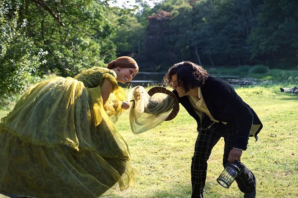 Elizabeth and Victor leaning over forward towards each other smiling while in a sunny nature setting. 