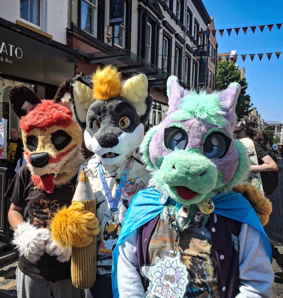 Three fursuiters posing together - a fox, a wolf-otter hybrid, and a Dutch angel dragon. 