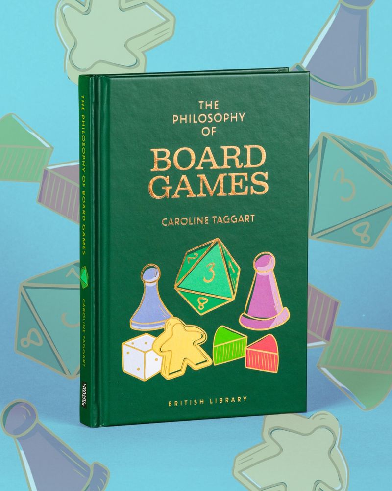 The Philosophy of Boardgames book against a blue background, with graphic boardgame pieces in the background. 
