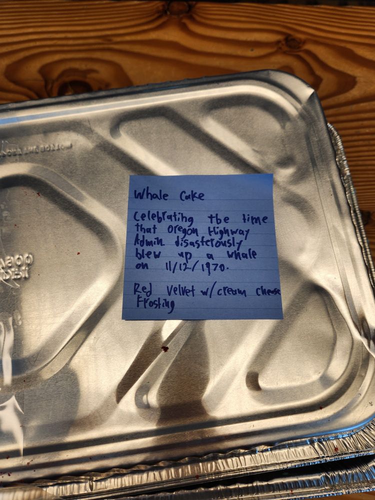 Note on a metal lid that says "whale cake celebrating the time that Oregon highway admin disastrously blew up a whale on 11/12/1970. Red velvet w cream cheese frosting"

