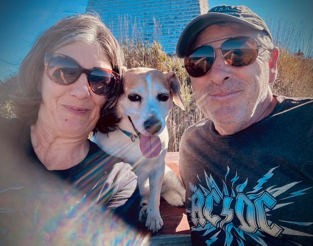 Family photo of left to right Lorraine, the account holder, Arthur Beagle, and Himself. 

A bright blue sky and the base of the Boars Head lighthouse are in the background. 

The photo is taken in bright sunlight and is washed out as a result. 