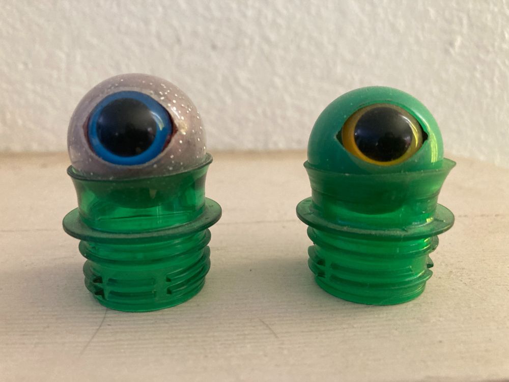 A picture of two plastic eyes, each sitting on a small pedestal made from the top of a plastic soda bottle.