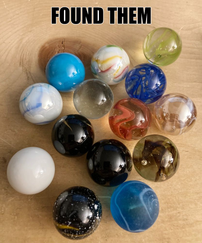 An image of assorted marbles on a pine board, with the text 'FOUND THEM' at the top.