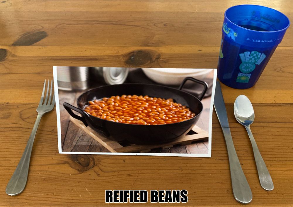 A picture of a cup, knife, spoon, and fork on a table, with a printed image of a bowl of beans in the center and the text "REIFIED BEANS" at the bottom.